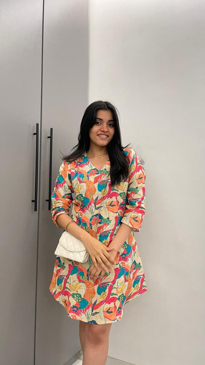 A woman in a colorful floral dress standing in front of a wardrobe
