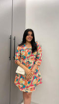 A woman in a colorful floral dress standing in front of a wardrobe