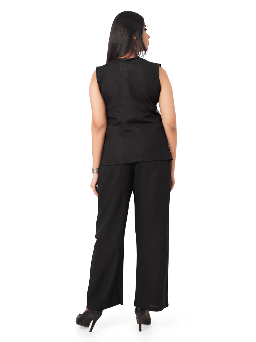 Woman wearing an asymmetric sleeveless linen top and wide-leg pants on a white background with back view