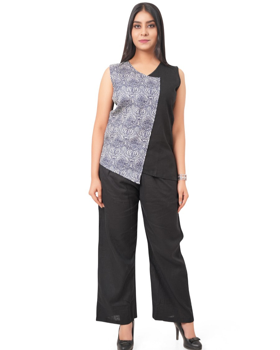 Woman wearing a monochrome linen top with a patterned design and black pants on a white background