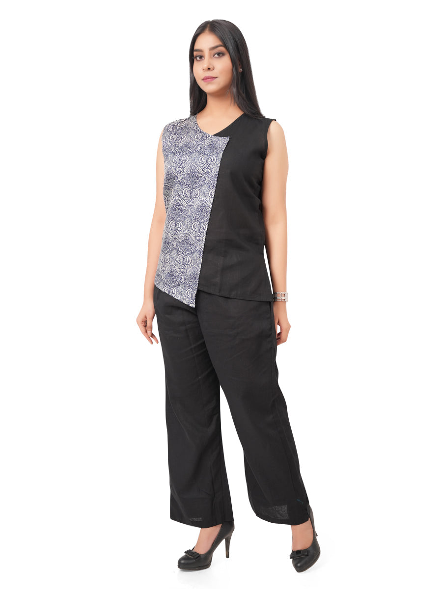 a woman wearing a black and patterned sleeveless linen top with black linen pants on a white background