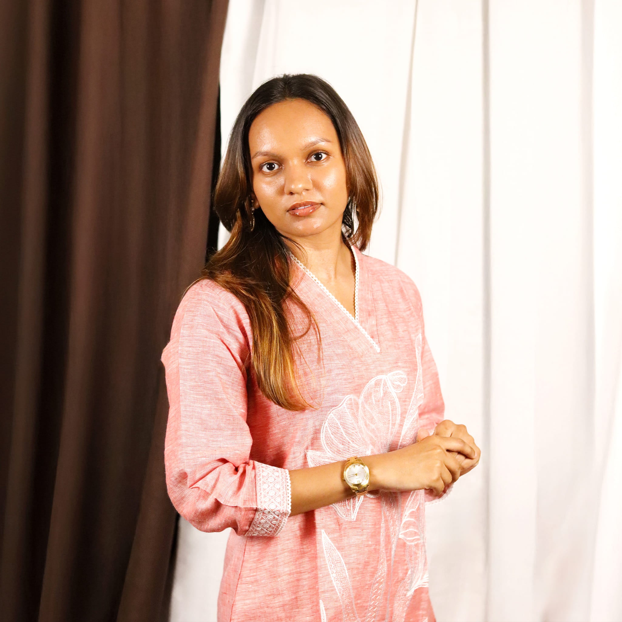 Woman wearing a rose-filled linen co-ord set outfit with a white curtain background