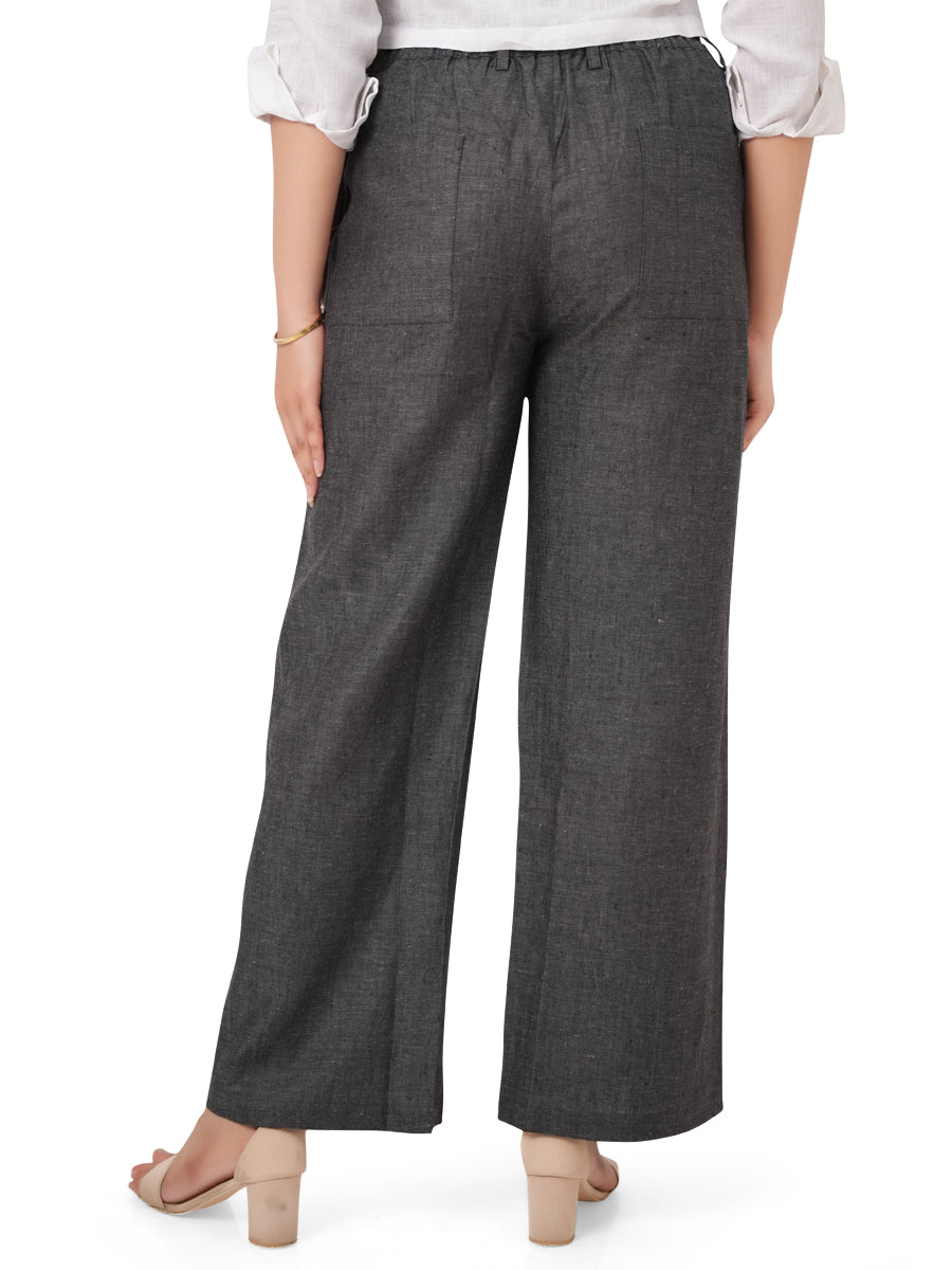 Person wearing charcoal black linen pants with a white shirt on a white background